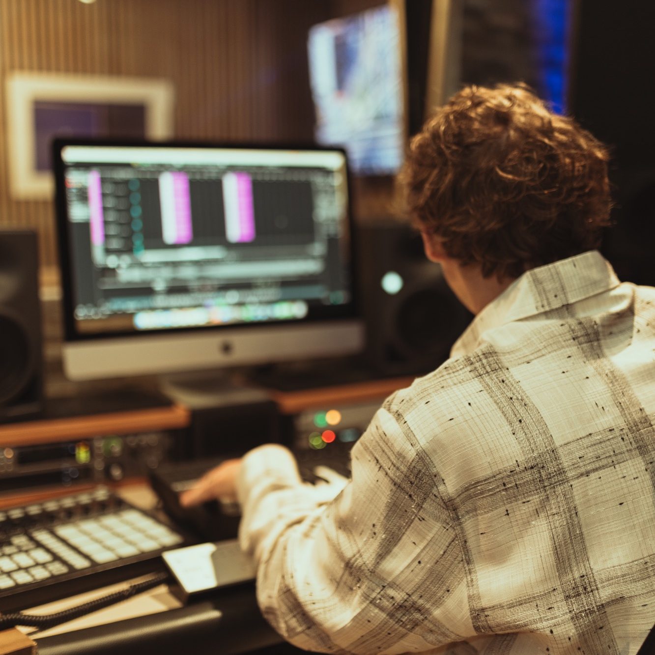 Junger Mann arbeitet an einem Computer mit Musiksoftware in einem Studio.