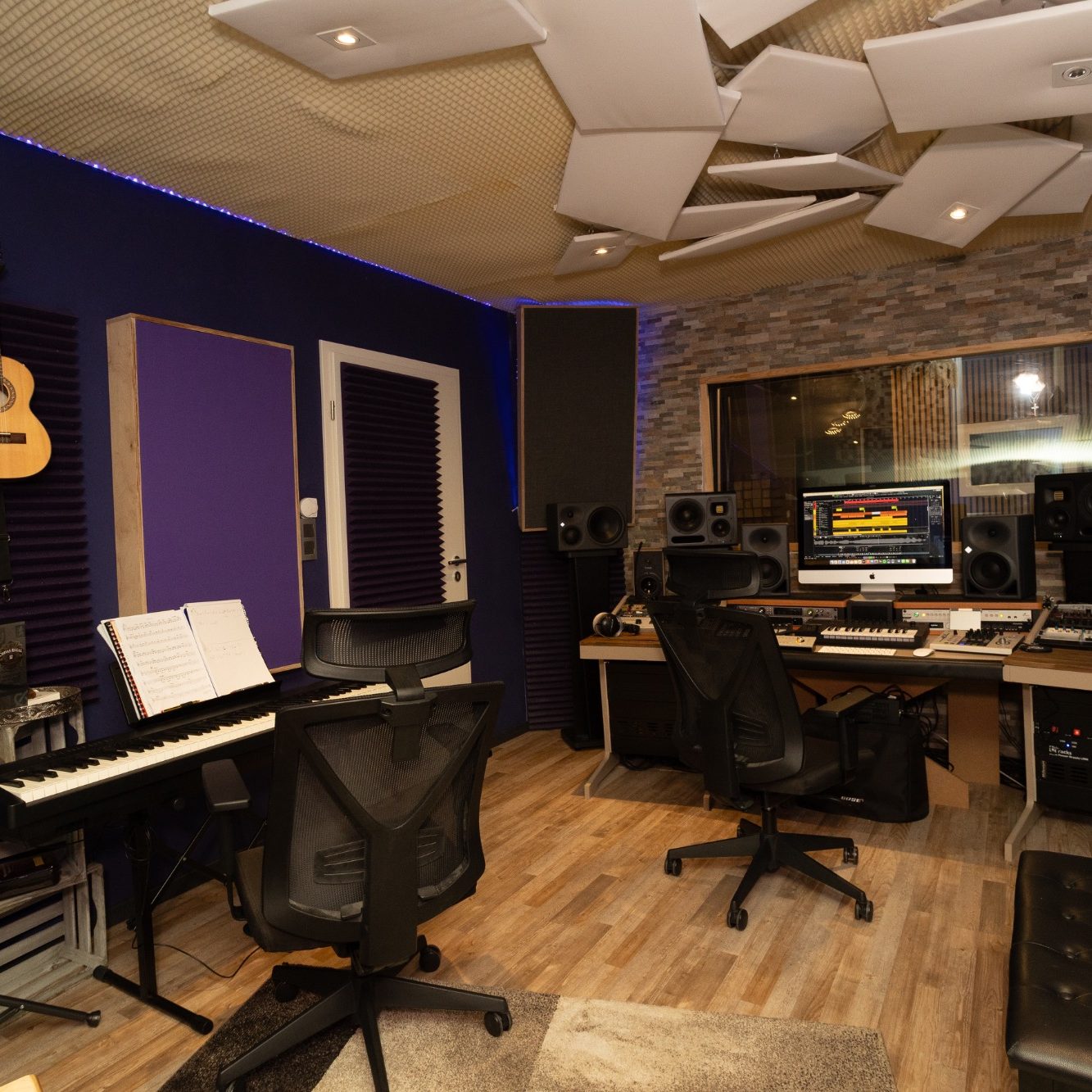 Moderne Musikproduktionsstudio mit Schreibtisch, Tastatur und Akustikpaneelen.