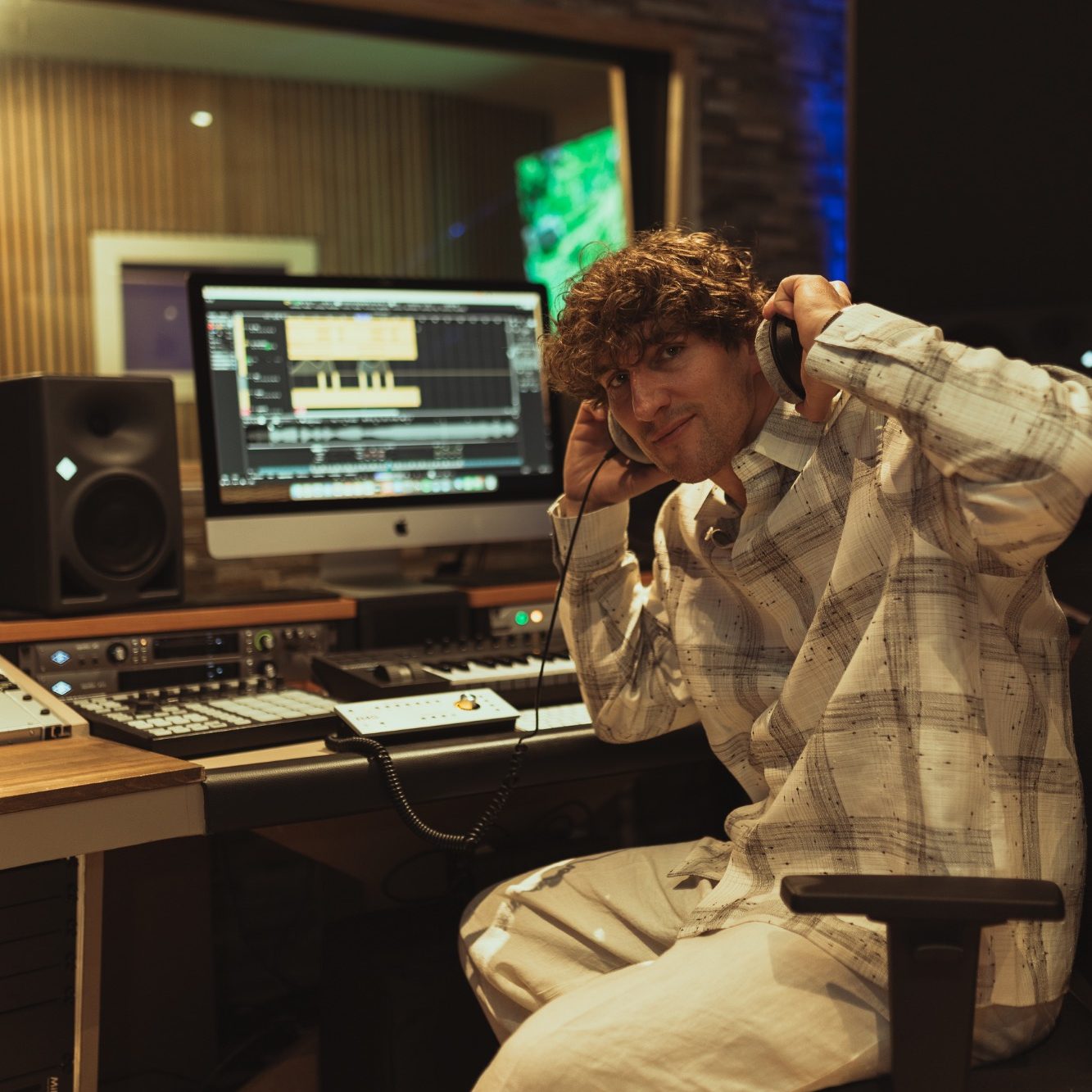 Junger Mann in einem Tonstudio mit Kopfhörern an einem Computer.
