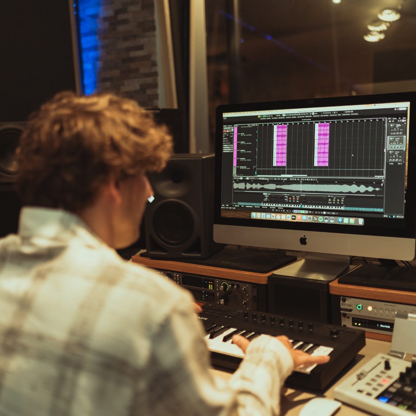 Junger Mann sitzt an einem Musikstudio-Computer und arbeitet an Musiksoftware.